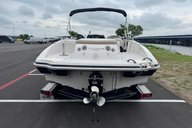 Slide: The Image of 2017 Tahoe 195 boat parked near a waterfront, showcasing rear view and trailer. - 11