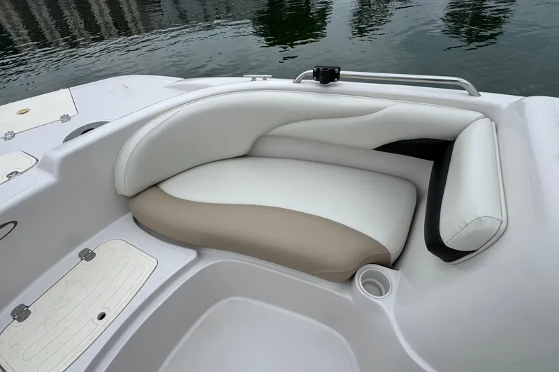 Slide: The Image of 2017 Tahoe 195 boat interior with white and beige cushioned seating by the water. - 14