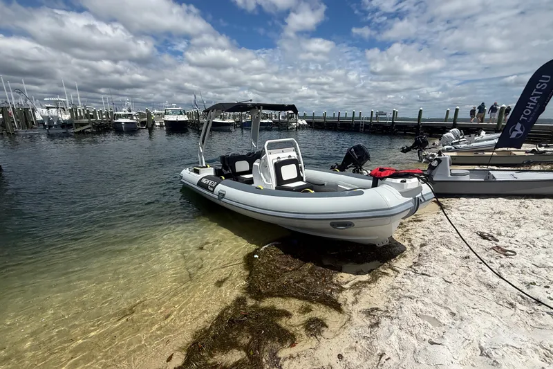 Slide: The Image of 2026 Highfield Velox 560 boat on sandy shore, near marina under cloudy sky. - 4