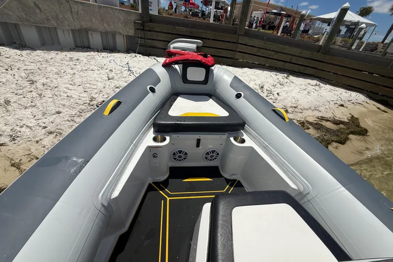 Slide: The Image of 2026 Highfield Velox 560 boat interior with seating, speakers, and cup holders on a sandy beach. - 8