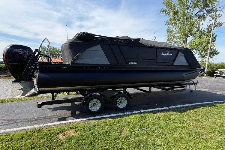 The Image of 2026 SunChaser Lucerne 22 LR DH Sport pontoon boat on trailer, covered and parked outdoors. - 0