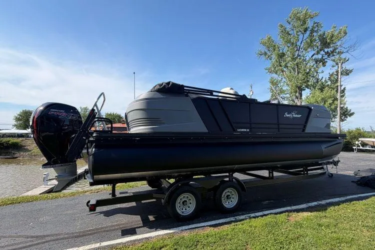 Slide: The Image of 2026 SunChaser Lucerne 22 LR DH Sport pontoon boat on trailer, parked near water. - 3
