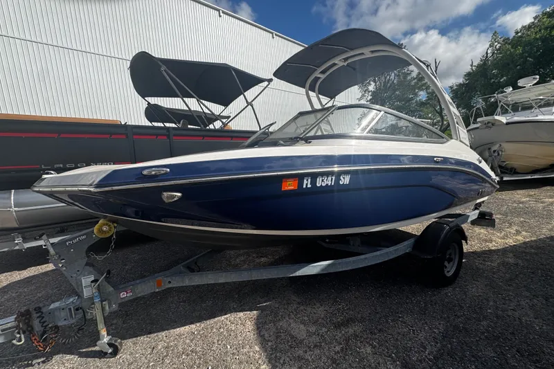 The Image of 2021 Yamaha Boats 195S on trailer, blue and white, parked outdoors under a clear sky. - 0