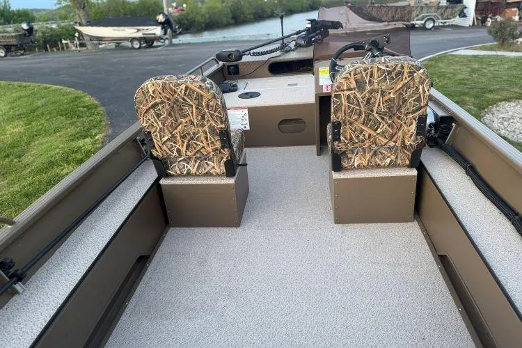 Slide: The Image of 2026 Smoker Craft Sportsman 1660 boat interior with camo seats and steering console. - 4