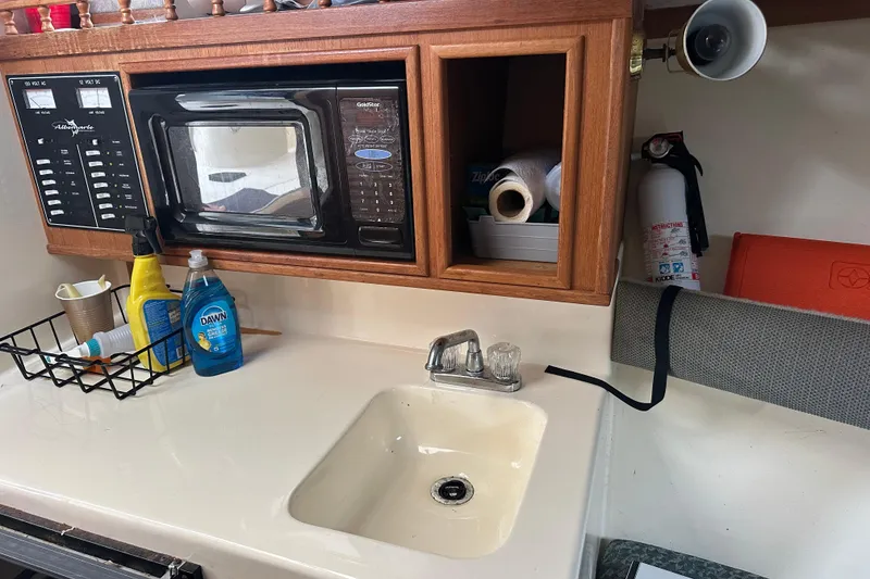 Slide: The Image of Kitchen area of a 2000 Albemarle 280 Express Fisherman with sink, microwave, and cleaning supplies. - 21