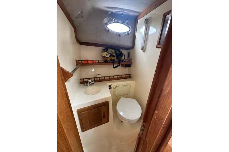 Slide: The Image of 2000 Albemarle 280 Express Fisherman boat bathroom with sink, toilet, and storage shelves. - 22