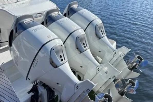 Slide: The Image of Triple outboard motors on a 2023 Schaefer 400 boat, docked on calm water. - 2