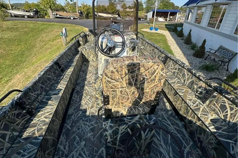 Slide: The Image of 2026 Smoker Craft Sportsman 1866 boat with camouflage interior, parked outdoors. - 4