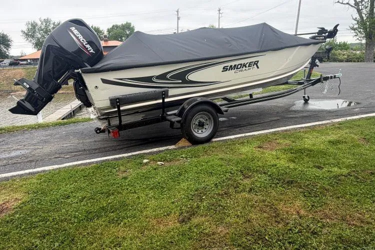 The Image of 2026 Smoker Craft Angler 16 SC boat on trailer, covered, with Mercury outboard motor. - 0