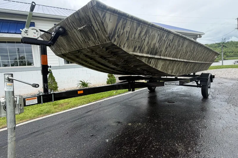 Slide: The Image of 2026 Smoker Craft 1448 Jon boat on a trailer, parked on wet pavement. - 4