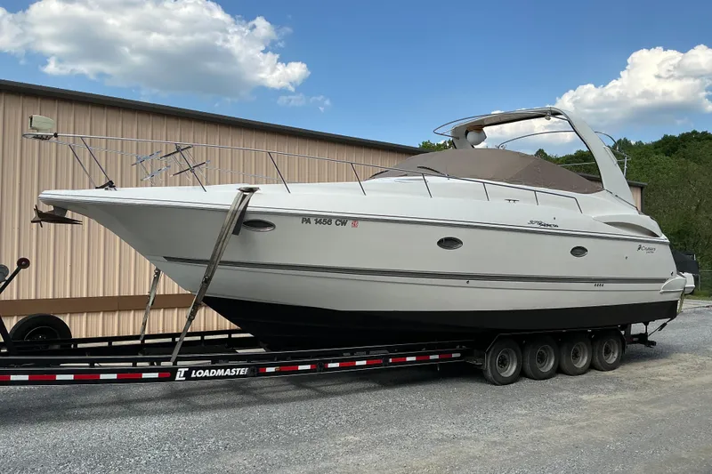 The Image of 2005 Cruisers Yachts 370 Express on trailer, parked outdoors under blue sky. - 1