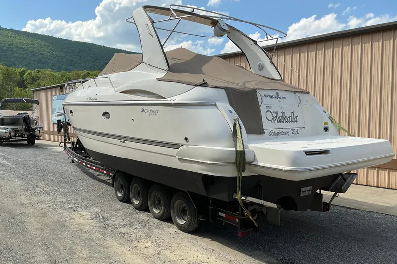 Slide: The Image of 2005 Cruisers Yachts 370 Express on trailer, parked near a building, with scenic background. - 6