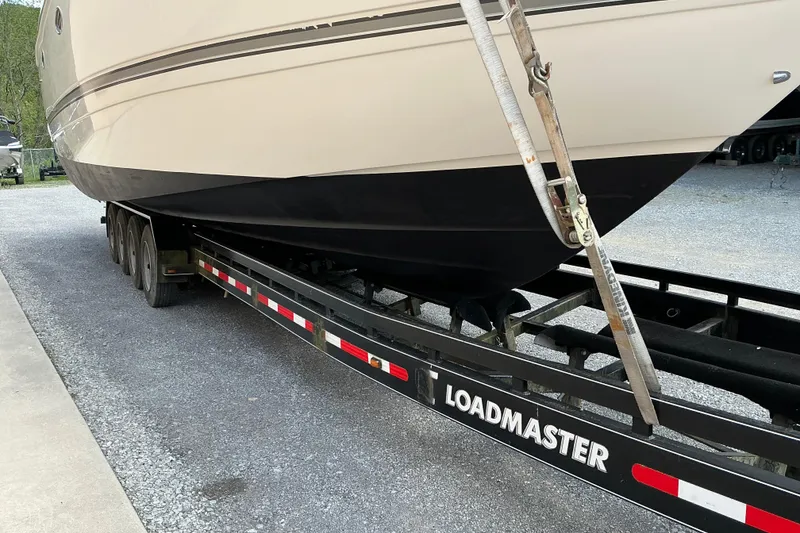 Slide: The Image of 2005 Cruisers Yachts 370 Express on Loadmaster trailer, parked on gravel. - 9