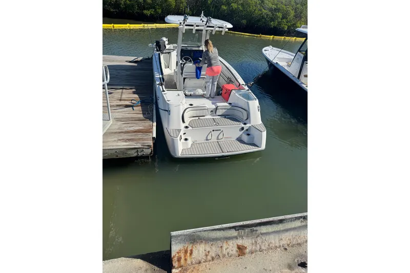 Slide: The Image of 2025 Yamaha Boats 255 FSH Sport H docked, rear view with person onboard. - 2