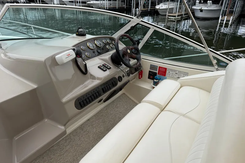Slide: The Image of 2004 Cruisers Yachts 320 Express helm with gauges, steering wheel, and white seating. - 4