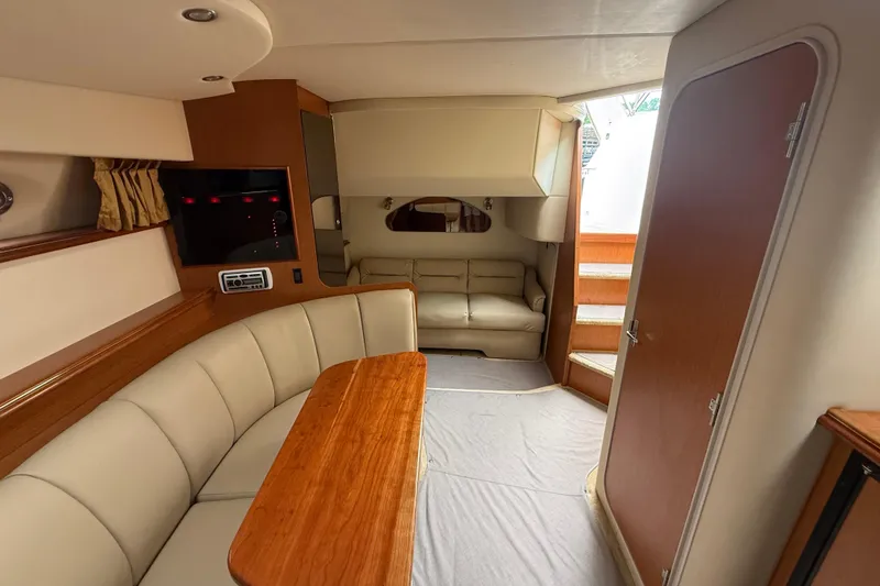 Slide: The Image of Interior of 2004 Cruisers Yachts 320 Express, featuring cozy seating and wooden accents. - 8