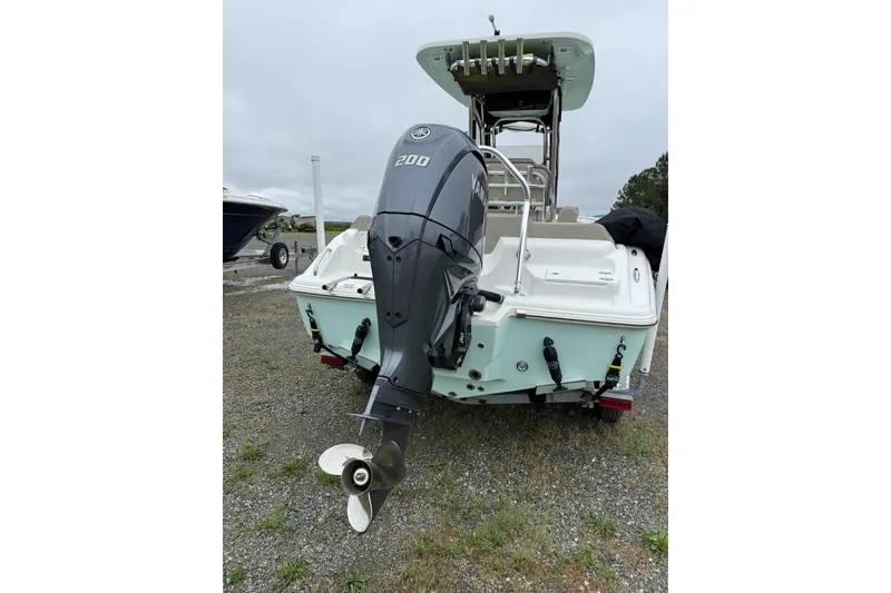 Slide: The Image of 2023 Key West 219 FS boat with powerful outboard motor, parked on gravel. - 6