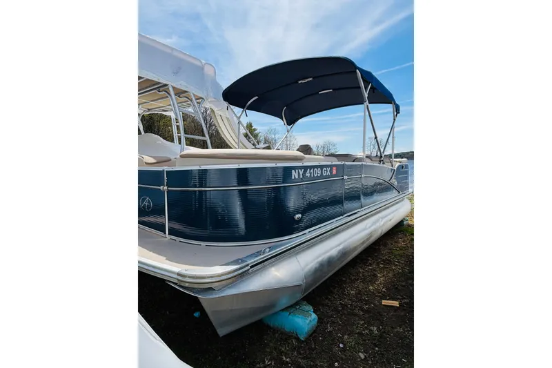 The Image of 2017 Avalon Catalina Cruise 21' pontoon boat with blue canopy, docked on shore. - 0