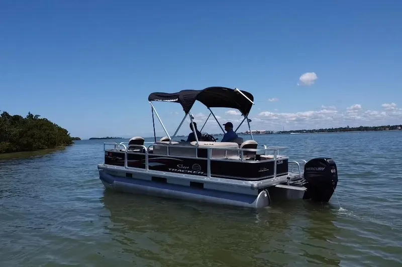 Slide: The Image of 2017 Sun Tracker Bass Buggy 18 DLX pontoon boat on calm water under clear blue sky. - 20