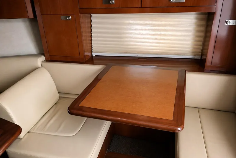 Slide: The Image of Interior of 2012 Sea Ray Sundancer 310, featuring a cozy dining area with wood accents. - 5