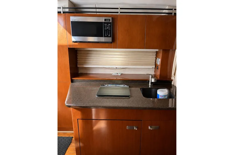 Slide: The Image of Interior of 2012 Sea Ray Sundancer 310, featuring a compact kitchen with microwave and sink. - 7
