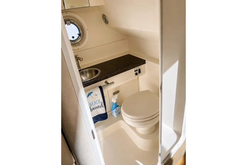 Slide: The Image of 2012 Sea Ray Sundancer 310 bathroom with sink, toilet, and porthole window. - 8