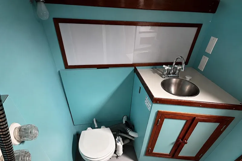 Slide: The Image of Vintage 1965 Pearson Countess 44 yacht bathroom with turquoise walls, sink, and toilet. - 10