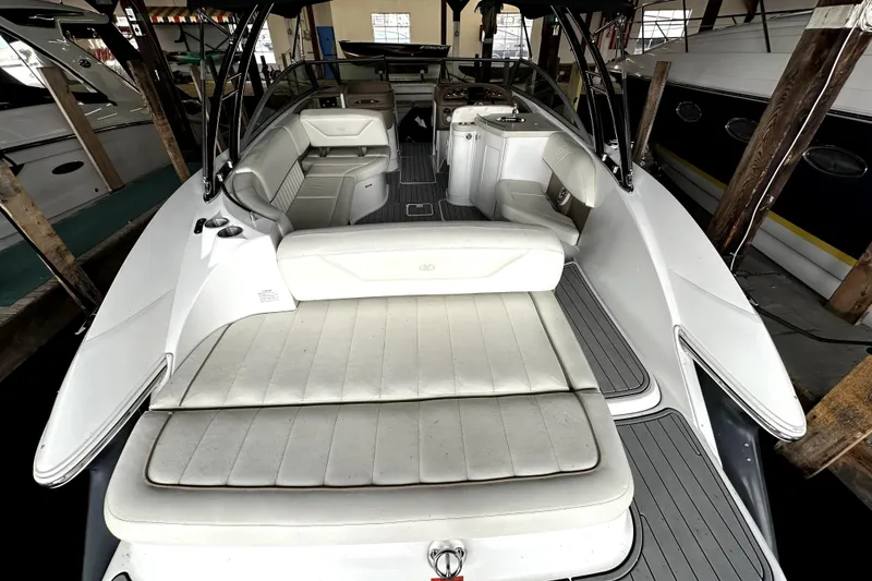 Slide: The Image of 2008 Cobalt 302 boat interior with white seating and sleek design in a marina setting. - 9