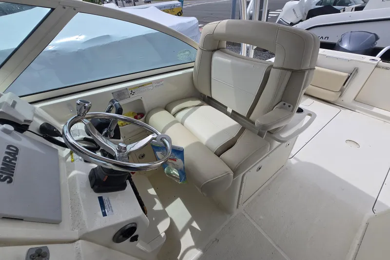 Slide: The Image of 2015 World Cat 295 DC boat interior with steering wheel and seating area. - 16