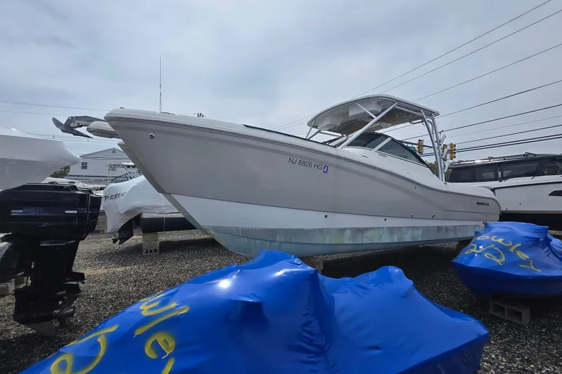 Slide: The Image of 2015 World Cat 295 DC boat on display, surrounded by other vessels and blue covers. - 22