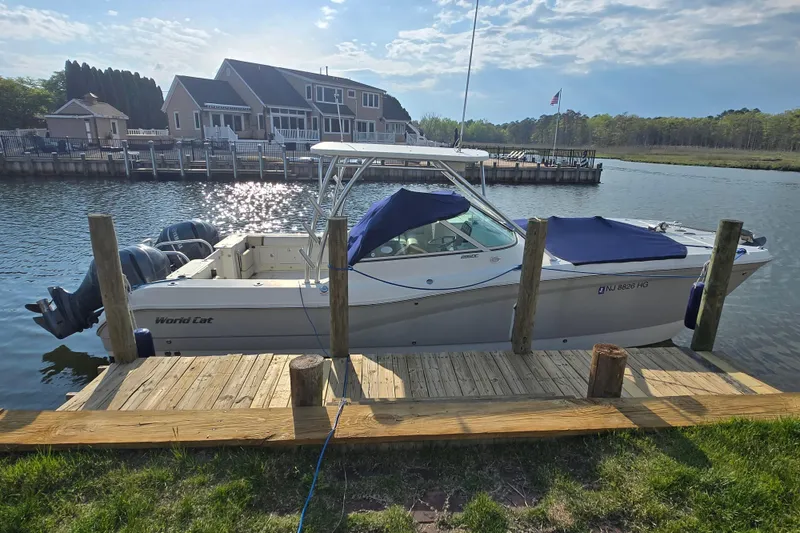 Slide: The Image of 2015 World Cat 295 DC boat docked by a waterfront home under a clear sky. - 5