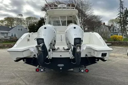 Slide: The Image of 2020 Pursuit OS 325 Offshore boat with dual outboard engines, parked on a residential street. - 3