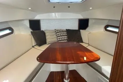 Slide: The Image of 2020 Pursuit OS 325 Offshore cabin interior with plush seating and wooden table. - 8