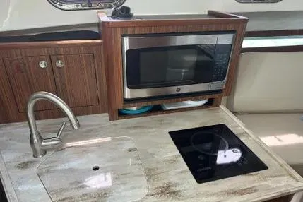 Slide: The Image of 2020 Pursuit OS 325 Offshore yacht kitchen with sink, microwave, and stovetop. - 9