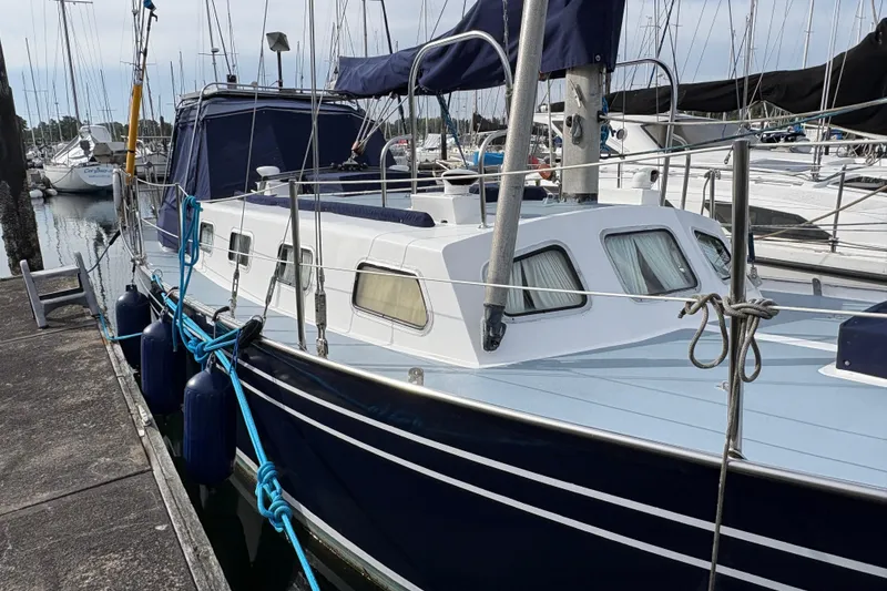 Slide: The Image of 1977 Folkes Full Keel Offshore Cutter docked at marina, featuring classic design and blue hull. - 11