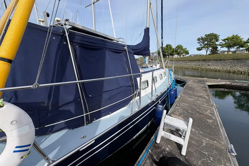 Slide: The Image of 1977 Folkes Full Keel Offshore Cutter docked, featuring blue canvas and safety equipment. - 15