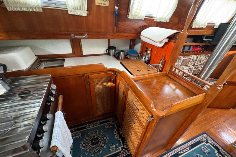 Slide: The Image of 1977 Folkes Full Keel Offshore Cutter interior with wooden cabinetry and compact kitchen area. - 52