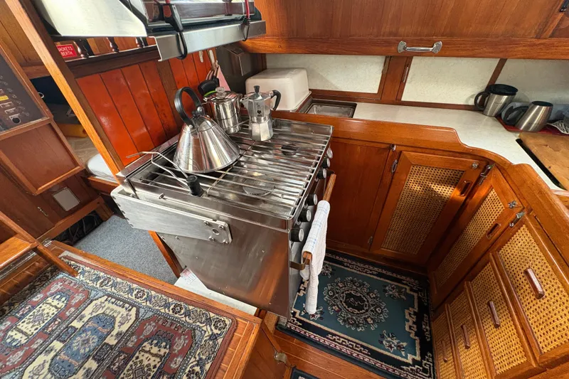 Slide: The Image of 1977 Folkes Full Keel Offshore Cutter galley with stove, wooden cabinetry, and nautical decor. - 54