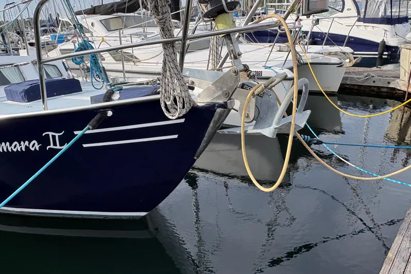 Slide: The Image of 1977 Folkes Full Keel Offshore Cutter docked, featuring anchor and mooring lines. - 6