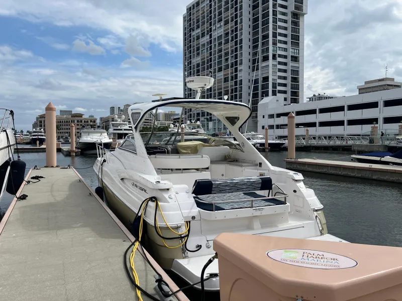 Slide: The Image of 2007 Regal 3760 Commodore yacht docked at a marina with cityscape background. - 2