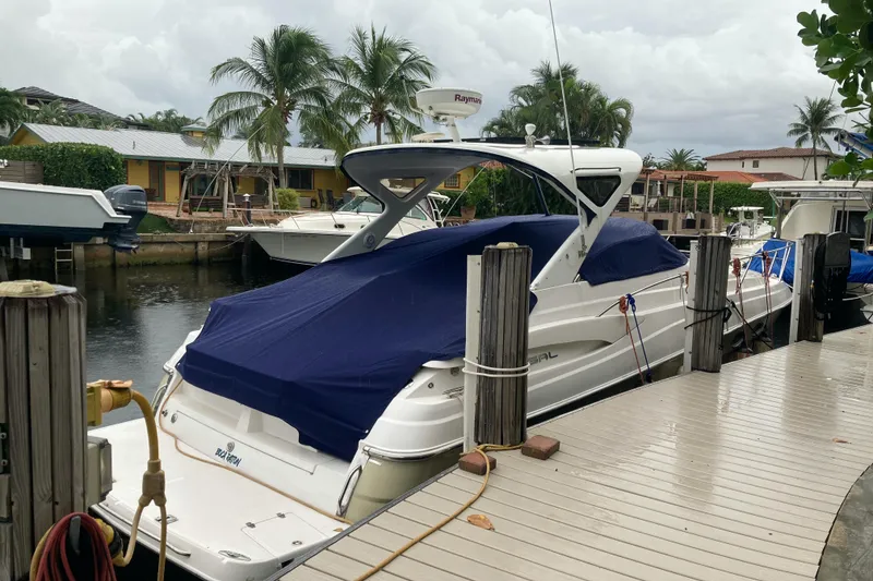 Slide: The Image of 2007 Regal 3760 Commodore yacht docked with blue cover, surrounded by palm trees. - 4