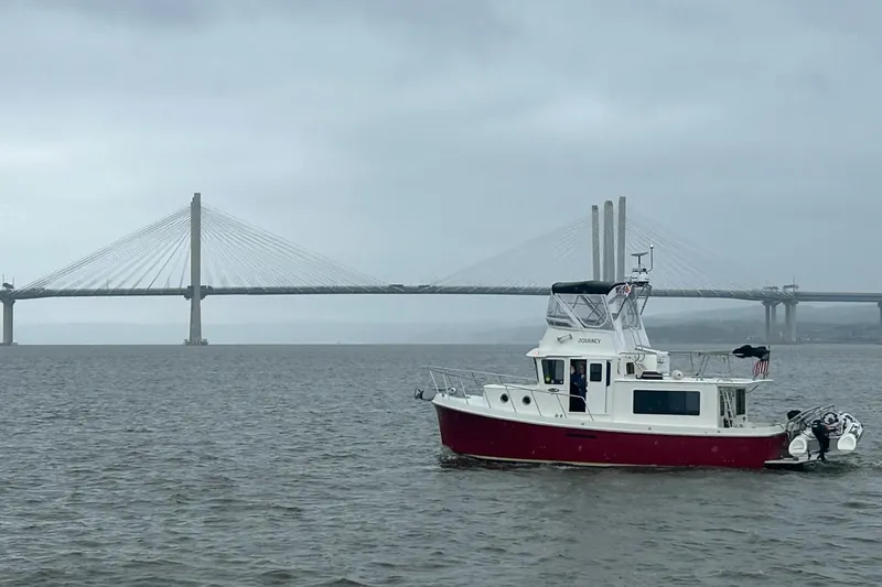 Slide: The Image of American Tug 365 Flybridge 2012 cruising near a large suspension bridge on a cloudy day. - 108