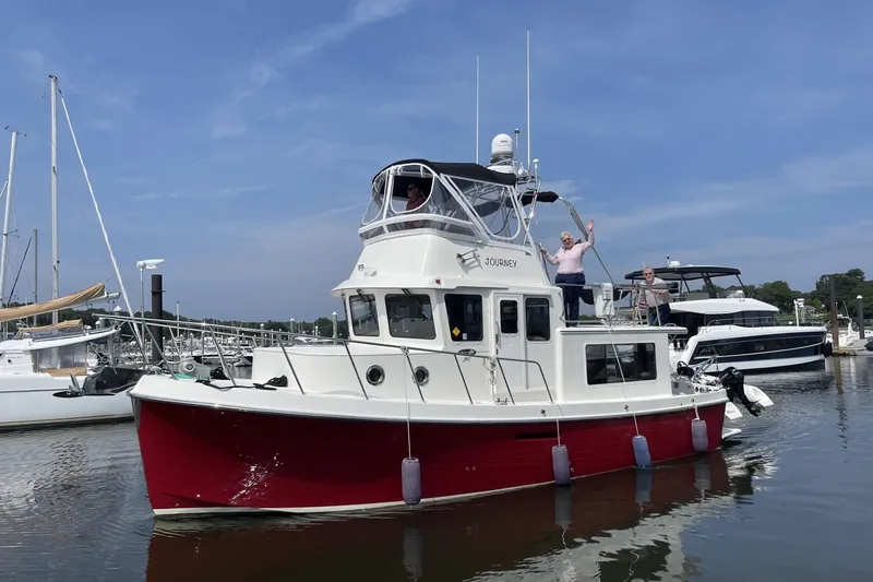 Slide: The Image of 2012 American Tug 365 Flybridge in marina, with people waving on deck. - 112