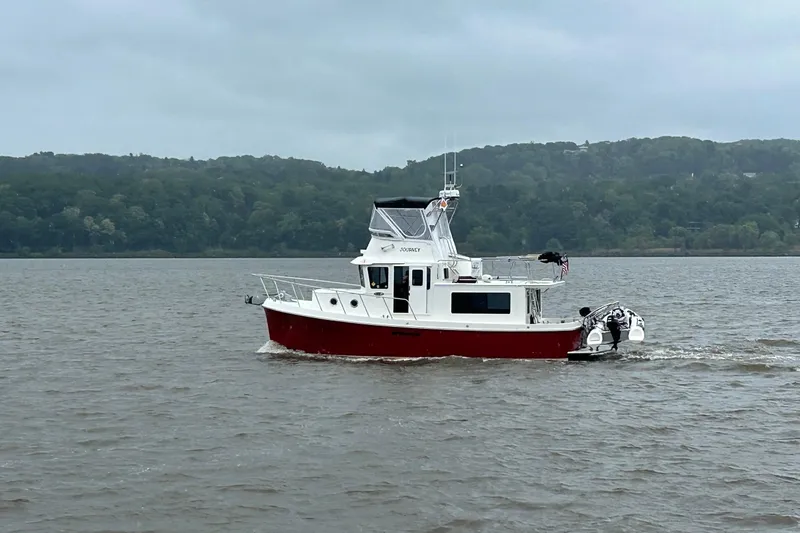 Slide: The Image of American Tug 365 Flybridge 2012 cruising on a calm river with forested hills in the background. - 114