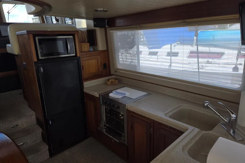 Slide: The Image of Interior of 2012 American Tug 365 Flybridge, featuring kitchen with microwave, stove, and sink. - 18