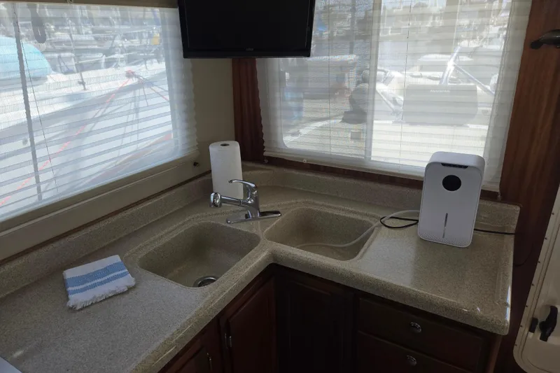 Slide: The Image of 2012 American Tug 365 Flybridge kitchen with dual sinks, countertop, and window view. - 20