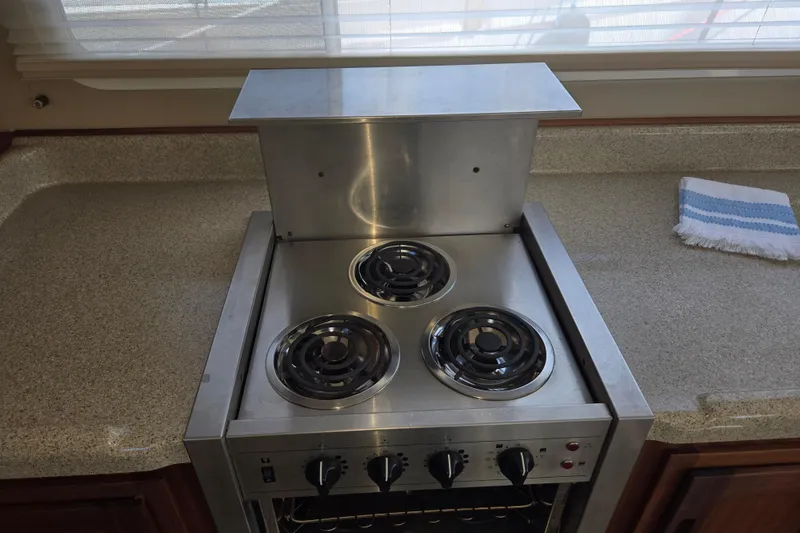 Slide: The Image of Electric stove in 2012 American Tug 365 Flybridge galley, featuring three burners and control knobs. - 22