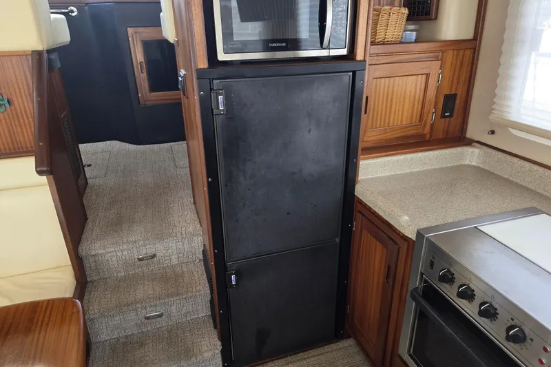 Slide: The Image of Interior of 2012 American Tug 365 Flybridge, featuring kitchen appliances and wooden cabinetry. - 24
