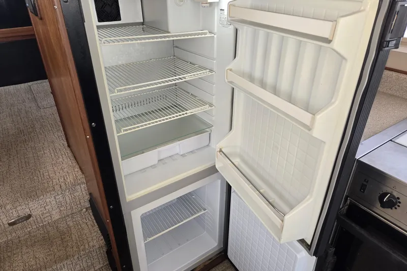 Slide: The Image of Open refrigerator inside 2012 American Tug 365 Flybridge, showcasing spacious interior and shelving. - 25