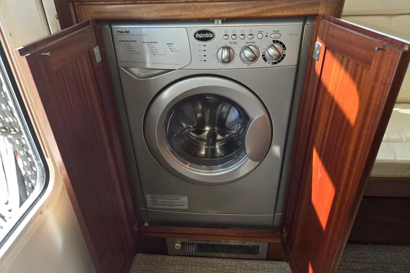 Slide: The Image of Washing machine inside 2012 American Tug 365 Flybridge, with wooden cabinet doors open. - 30